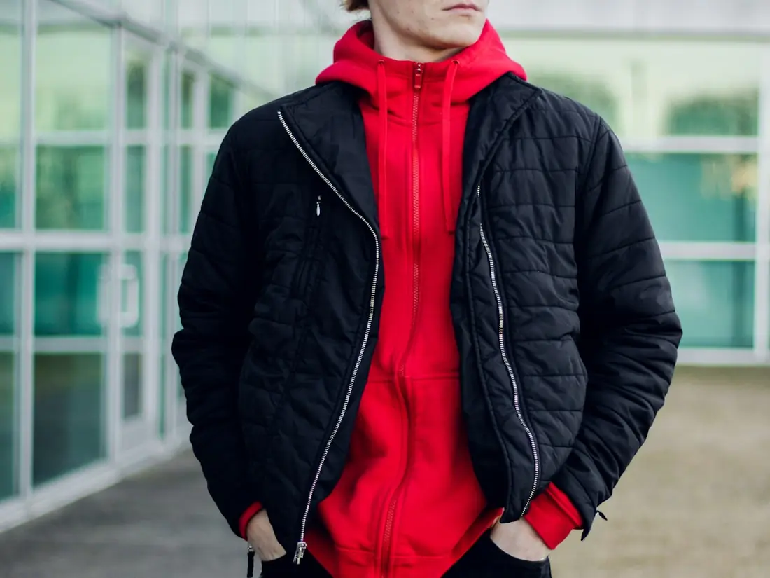 A layered winter outfit: red insulated hoodie worn under a quilted navy shell jacket